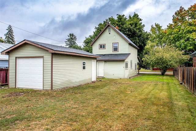 rear view of house with an outdoor structure, a garage, and a lawn