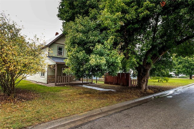 view of property hidden behind natural elements with covered porch and a front lawn