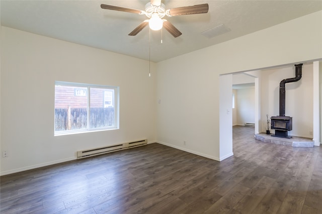 empty room featuring a wood stove, a baseboard radiator, ceiling fan, and dark hardwood / wood-style floors