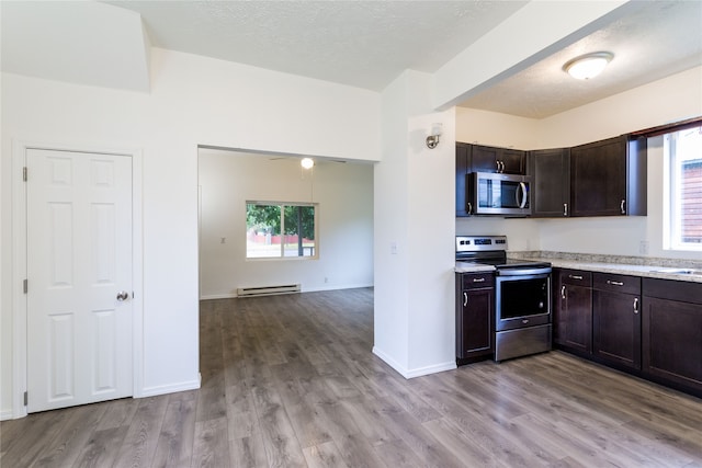 kitchen featuring baseboard heating, plenty of natural light, stainless steel appliances, and light hardwood / wood-style floors