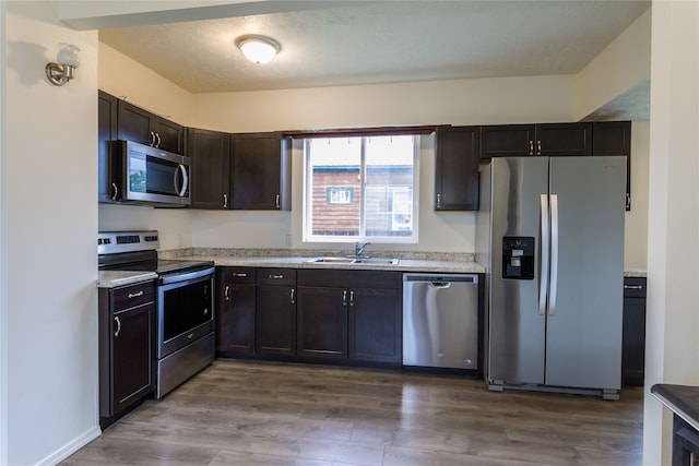 kitchen with hardwood / wood-style floors, stainless steel appliances, dark brown cabinets, and sink