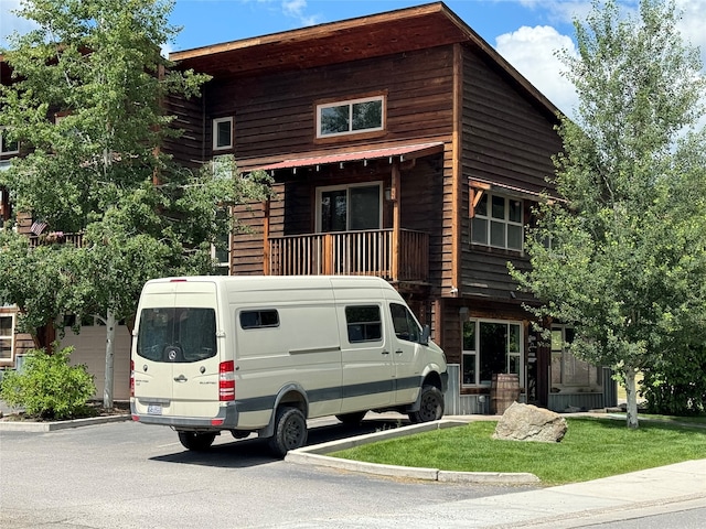 view of front facade featuring a front lawn, a garage, and a balcony