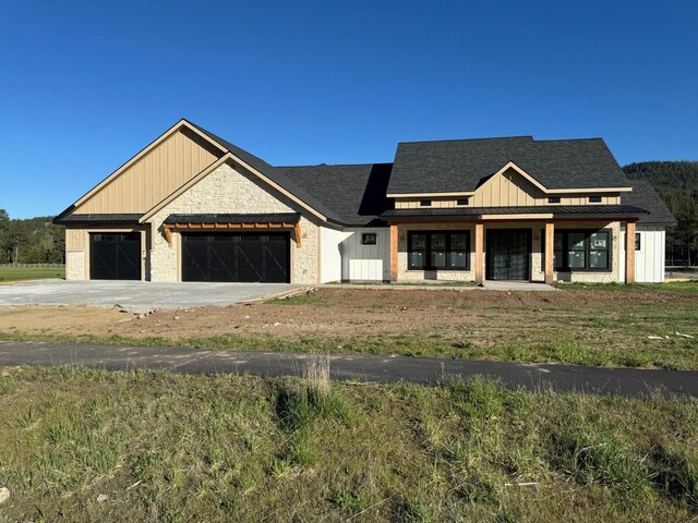 modern farmhouse featuring board and batten siding, a garage, concrete driveway, stone siding, and covered porch