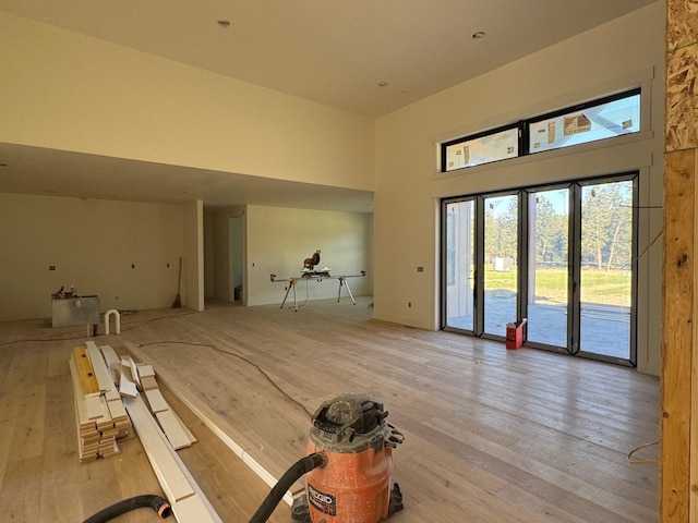 unfurnished living room featuring a high ceiling and light wood finished floors