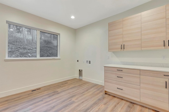 laundry room featuring cabinets, hookup for an electric dryer, hookup for a washing machine, and light hardwood / wood-style flooring