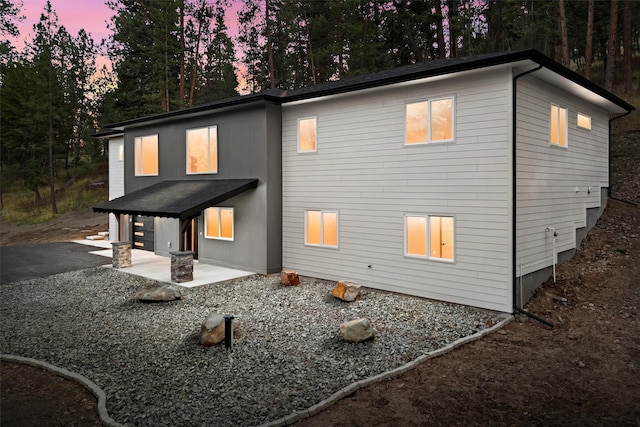 back house at dusk featuring a patio