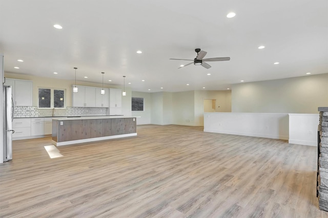 unfurnished living room with ceiling fan, sink, and light hardwood / wood-style flooring