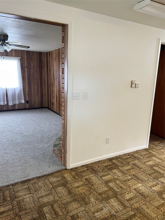 unfurnished room featuring a textured ceiling, ceiling fan, and wooden walls