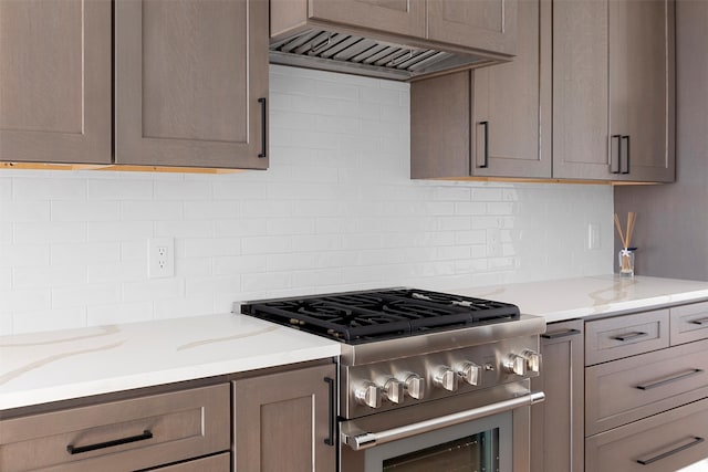 kitchen featuring ventilation hood, light stone counters, and stainless steel range