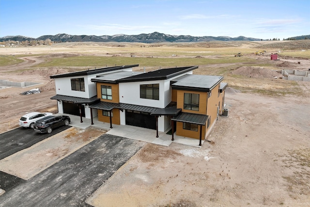 view of front of house with a mountain view, a rural view, and central AC unit