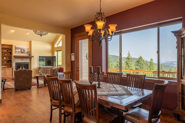 dining space with lofted ceiling, hardwood / wood-style flooring, and a notable chandelier