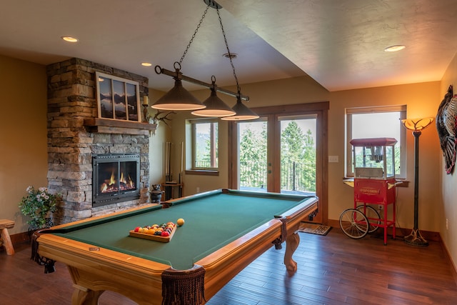 rec room with pool table, a stone fireplace, and dark hardwood / wood-style flooring