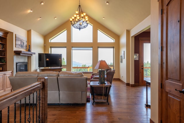 living room with dark wood-type flooring, a notable chandelier, high vaulted ceiling, and a tile fireplace