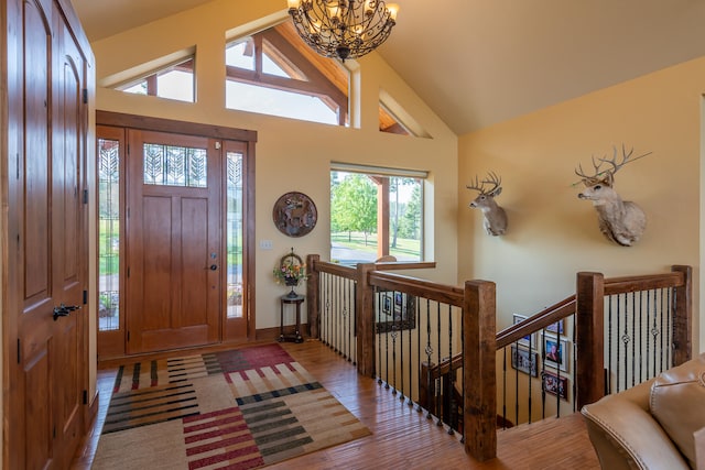 foyer entrance with high vaulted ceiling, a chandelier, and light hardwood / wood-style flooring