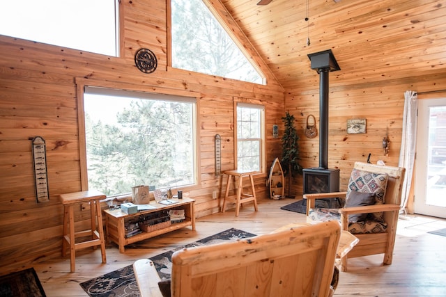 living room featuring wood walls, beamed ceiling, a wood stove, hardwood / wood-style floors, and high vaulted ceiling