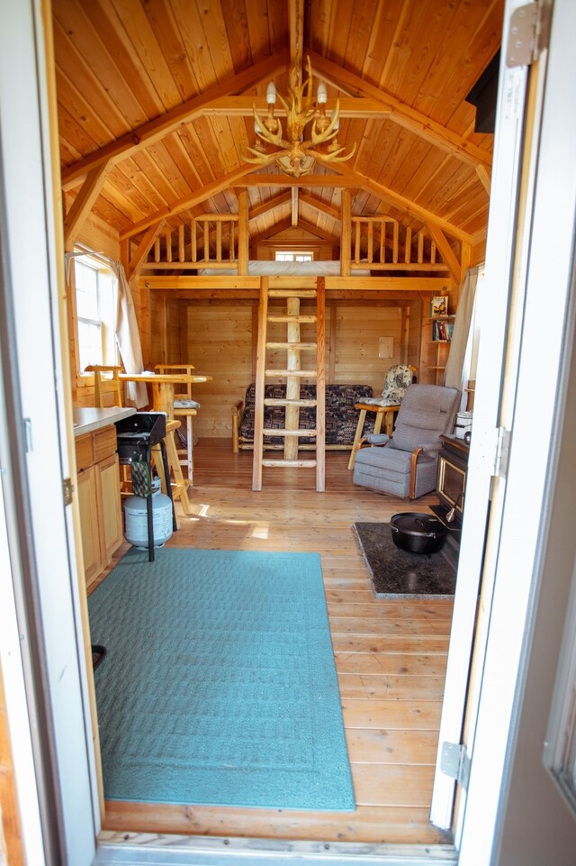 misc room featuring light wood-type flooring, a notable chandelier, wood walls, vaulted ceiling with beams, and wood ceiling