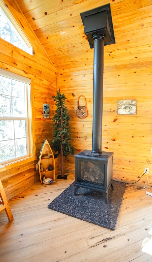 interior details with hardwood / wood-style floors, a wood stove, wood walls, and wooden ceiling