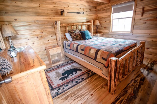 bedroom with hardwood / wood-style flooring and wooden walls