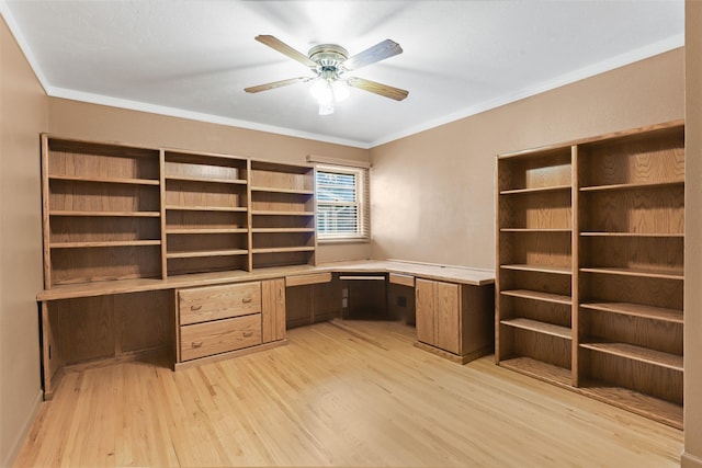 unfurnished office featuring ornamental molding, built in desk, ceiling fan, and light hardwood / wood-style flooring