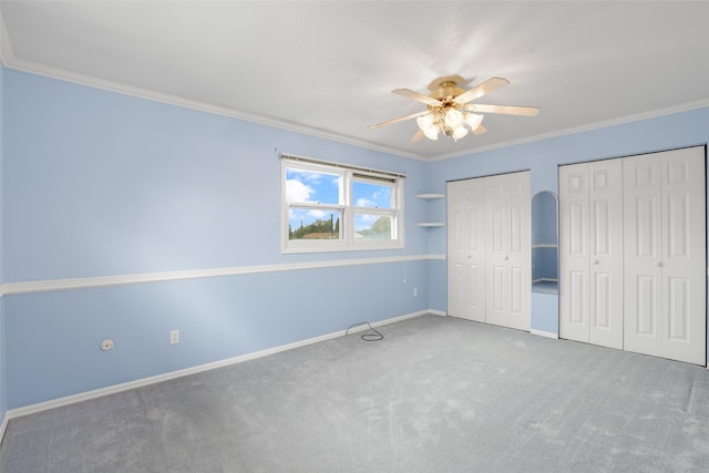 unfurnished bedroom featuring two closets, carpet floors, ornamental molding, and ceiling fan