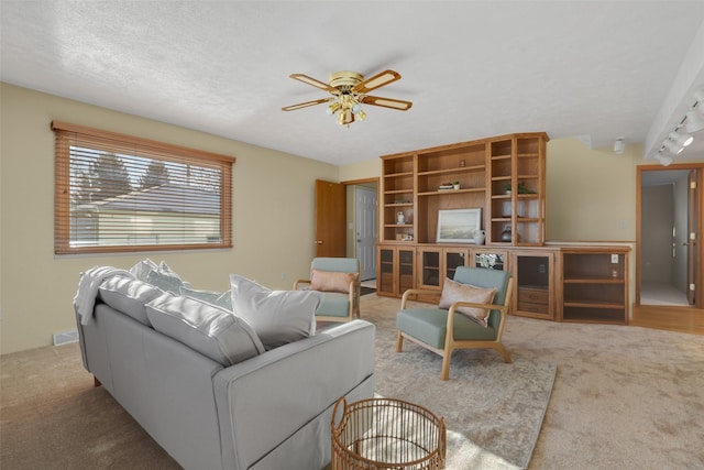 carpeted living room with ceiling fan and a textured ceiling