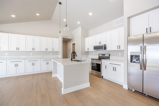 kitchen featuring a kitchen island with sink, stainless steel appliances, white cabinets, decorative light fixtures, and sink