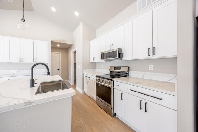 kitchen featuring hanging light fixtures, stainless steel appliances, lofted ceiling, white cabinetry, and sink