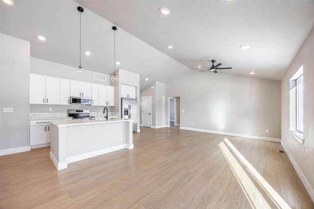 kitchen with white cabinets, ceiling fan, an island with sink, hanging light fixtures, and appliances with stainless steel finishes