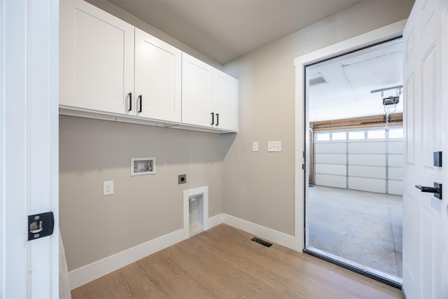 clothes washing area with electric dryer hookup, washer hookup, light hardwood / wood-style floors, and cabinets