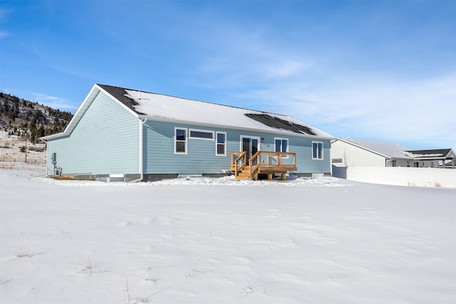 snow covered rear of property with a deck