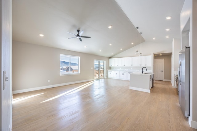 kitchen featuring a kitchen island with sink, ceiling fan, sink, white cabinetry, and decorative light fixtures