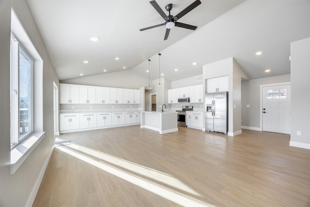 kitchen with a center island with sink, stainless steel appliances, pendant lighting, plenty of natural light, and white cabinets