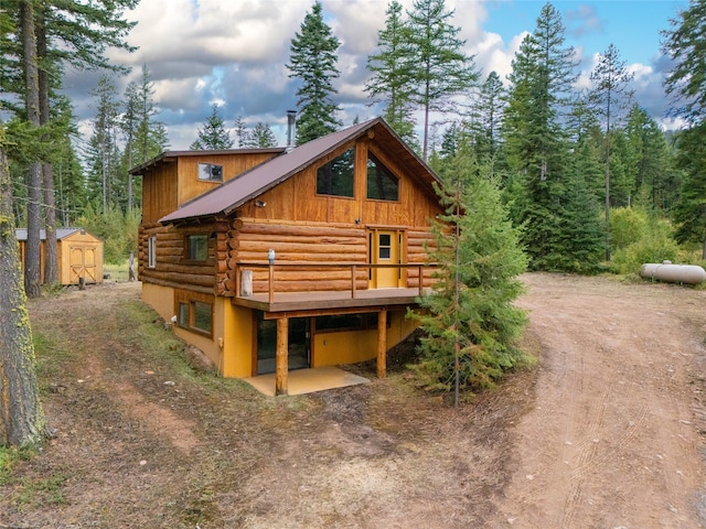 back of property featuring a storage shed and a deck