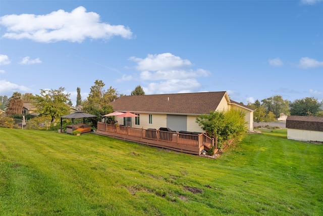 rear view of property with a wooden deck, a lawn, and a gazebo