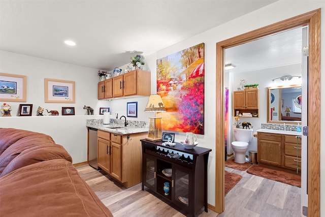 kitchen with stainless steel dishwasher, sink, and light hardwood / wood-style flooring