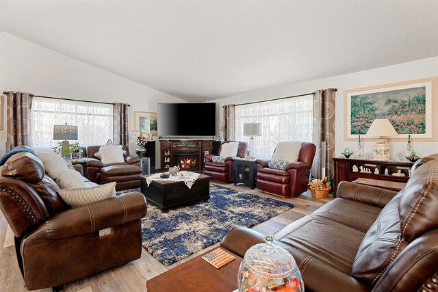 living room with lofted ceiling, a wealth of natural light, and light hardwood / wood-style flooring