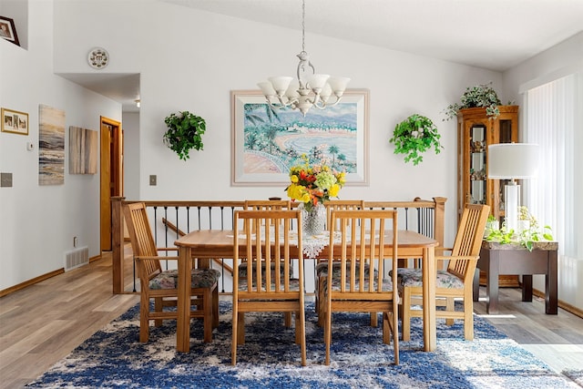 dining area featuring light hardwood / wood-style flooring, an inviting chandelier, and vaulted ceiling