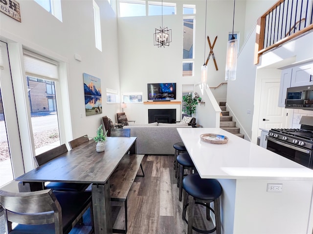 kitchen with a high ceiling, range with gas cooktop, hanging light fixtures, hardwood / wood-style flooring, and a breakfast bar area