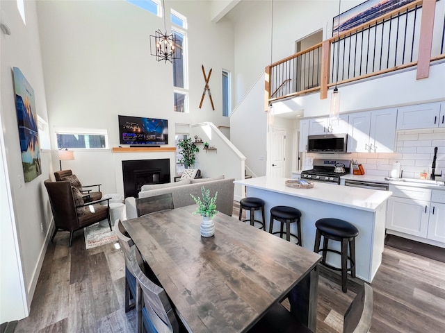 dining area featuring a towering ceiling, hardwood / wood-style flooring, a notable chandelier, and sink