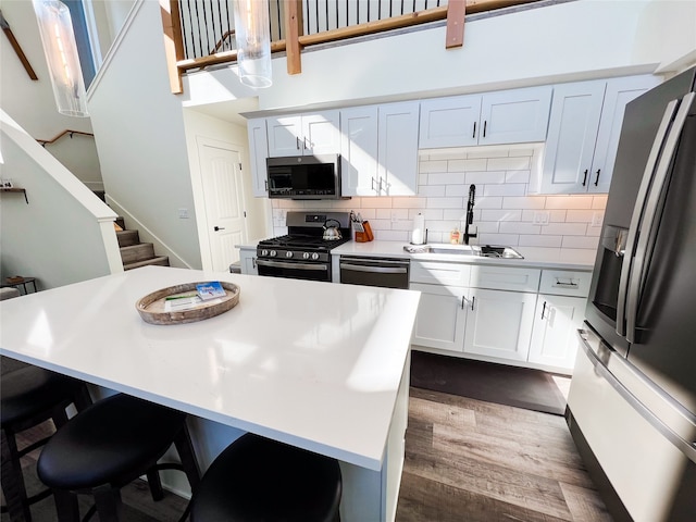 kitchen with dark wood-type flooring, stainless steel appliances, white cabinets, and a kitchen island