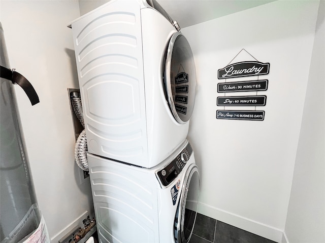 laundry room featuring dark tile patterned flooring and stacked washer and dryer