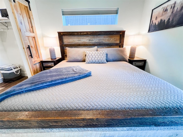 unfurnished bedroom with hardwood / wood-style flooring and a barn door