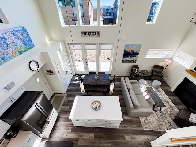 living room with a towering ceiling and dark hardwood / wood-style floors