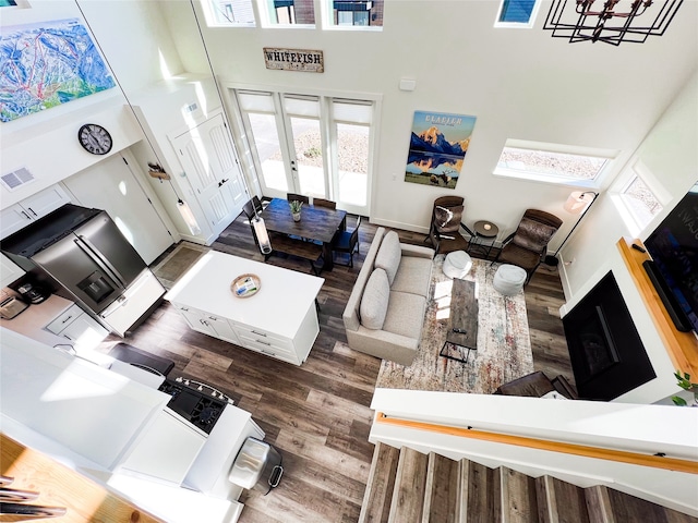 living room featuring plenty of natural light, a high ceiling, dark hardwood / wood-style floors, and french doors