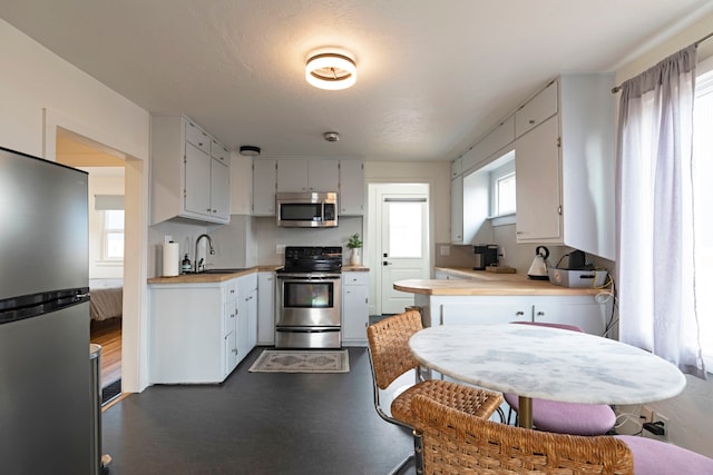 kitchen with appliances with stainless steel finishes, white cabinetry, and sink