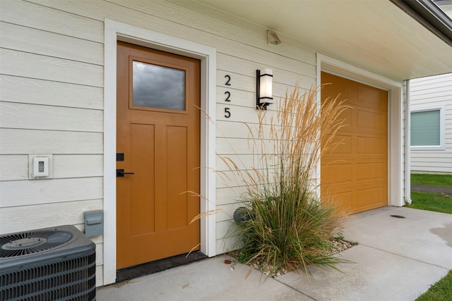 entrance to property featuring a garage and cooling unit