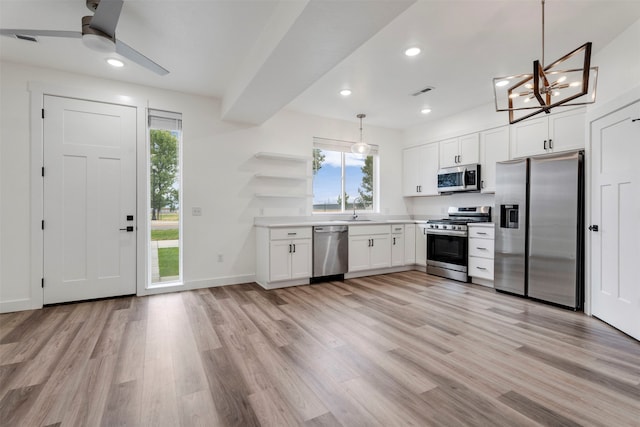 kitchen featuring appliances with stainless steel finishes, light hardwood / wood-style floors, white cabinets, and pendant lighting