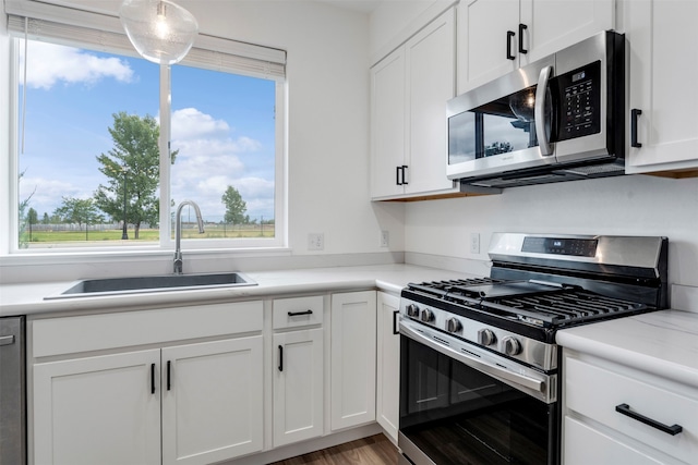 kitchen featuring hardwood / wood-style floors, appliances with stainless steel finishes, white cabinetry, and sink