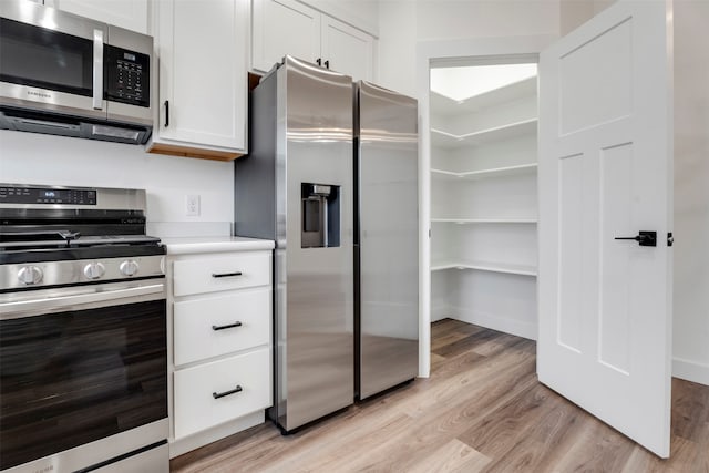 kitchen featuring light wood-type flooring, appliances with stainless steel finishes, and white cabinets