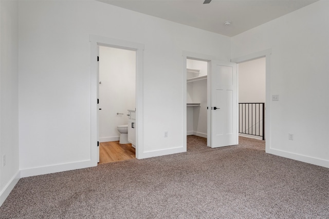 unfurnished bedroom featuring a closet, carpet flooring, a spacious closet, and ensuite bathroom